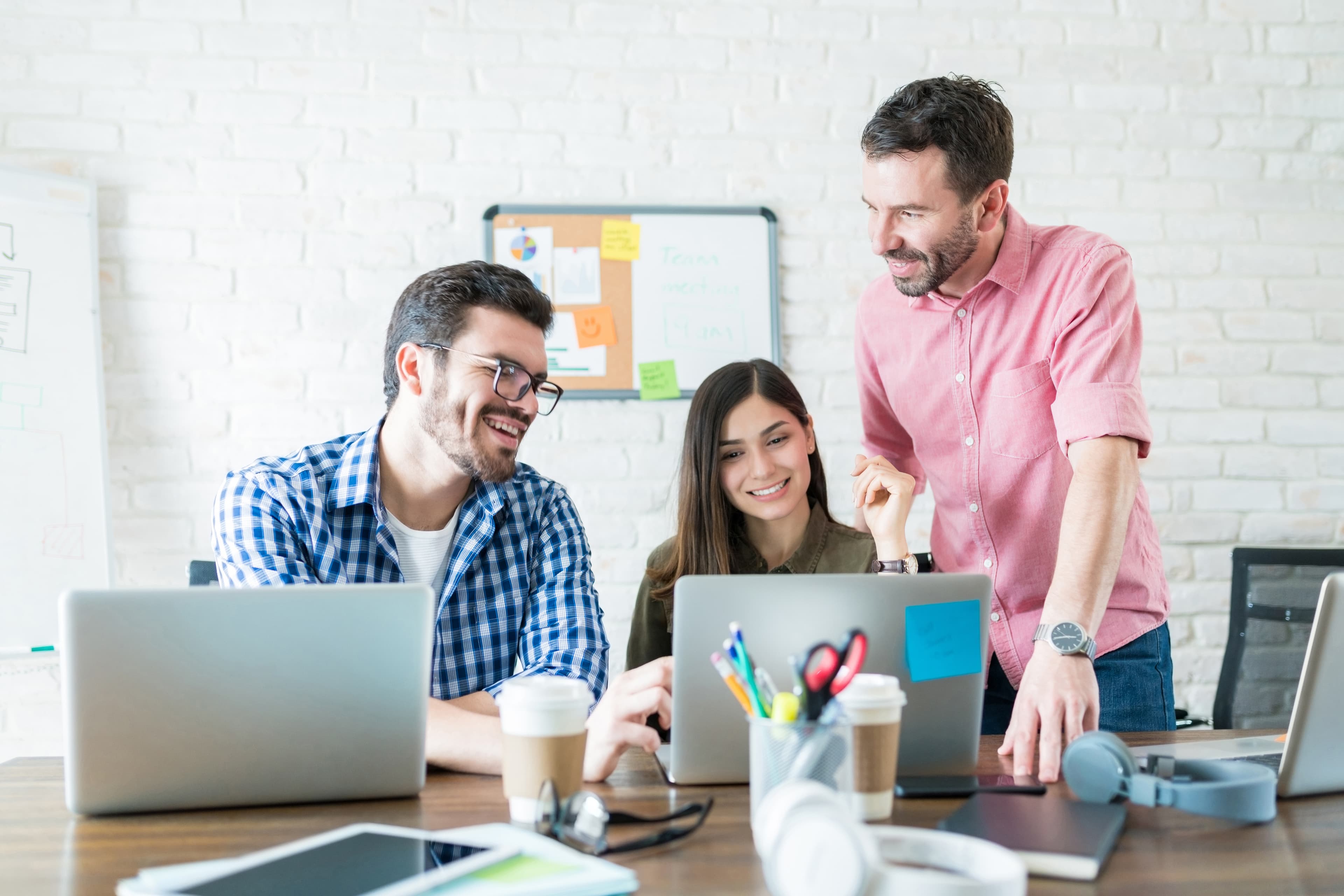 Three Cozmiq teammates reviewing work together on laptops